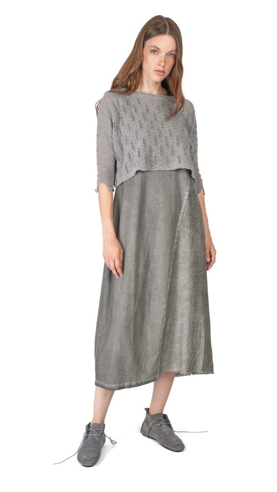 Frau trägt graues oversized Cropped-Kleid mit Strick-Oberteil und langem Rock, kombiniert mit bequemen Schuhen.