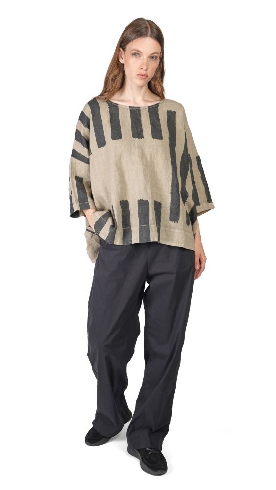 Frau trägt oversized gestreiftes Top mit weitem Schnitt und schwarze, weite Hosen, bequeme Schuhe.
