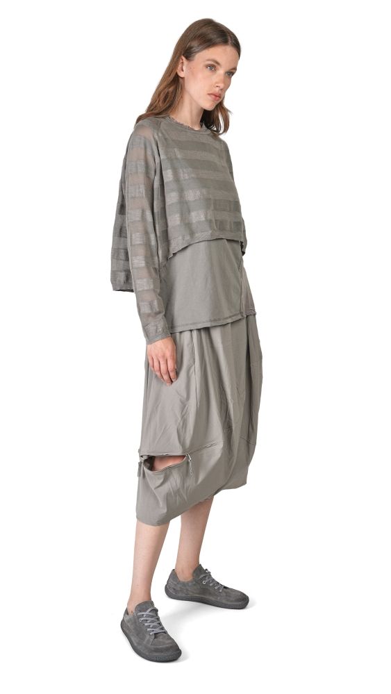 Frau trägt oversized graues Kleid mit Schlitz und gestreiftem Oberteil, bequeme Sneaker.