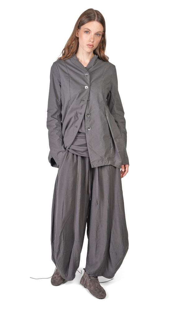 Frau trägt oversized graue Bluse mit Weste und weiten, knielangen Hosen, bequeme Schuhe.