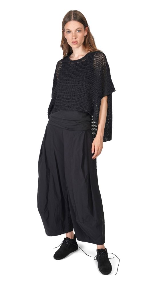 Frau trägt oversized schwarzes Netzhemd mit weitem Hosenrock und schwarzen Schuhen.