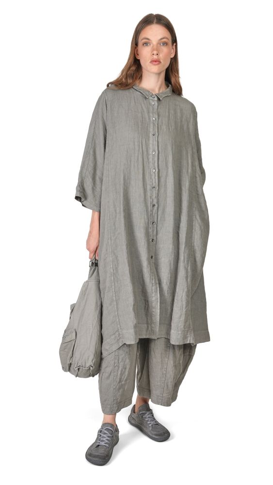 Frau trägt oversized graue Bluse mit weitem Rock und hält Stofftasche, bequeme Sneaker.
