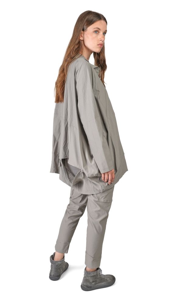 Frau trägt oversized graue Bluse mit weitem Schnitt und graue Cargo-Pantalons, steht seitlich.