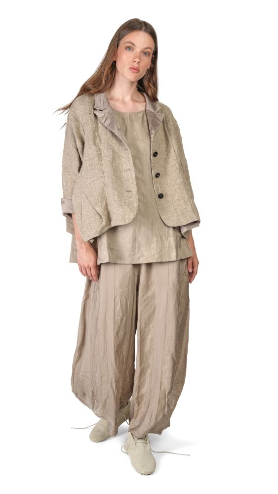 Frau trägt beigefarbenes, oversized Blazer-Set mit weiten Hosen und flachen Schuhen.