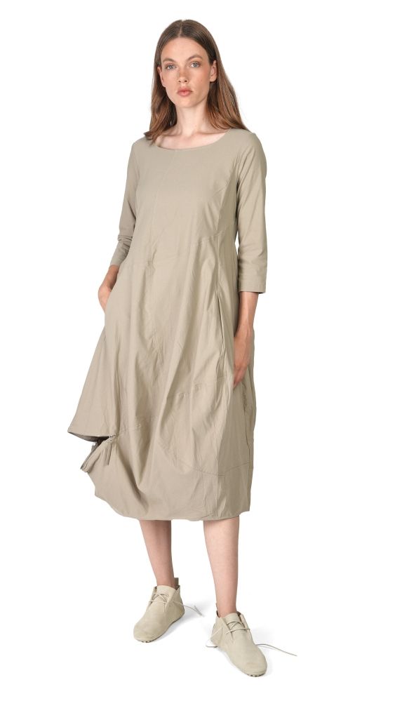 Frau trägt beiges, langes, weit geschnittenes Kleid mit 3/4 Ärmeln und bequemen Schuhen.
