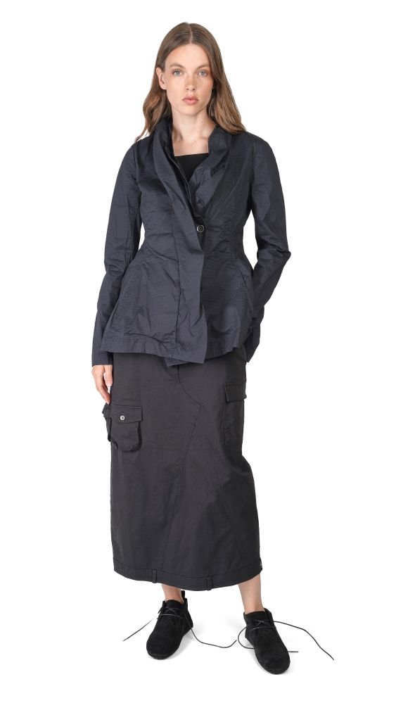 Frau trägt oversized schwarze Bluse mit weitem Rock und schwarzen Schuhen, lässiger Look.