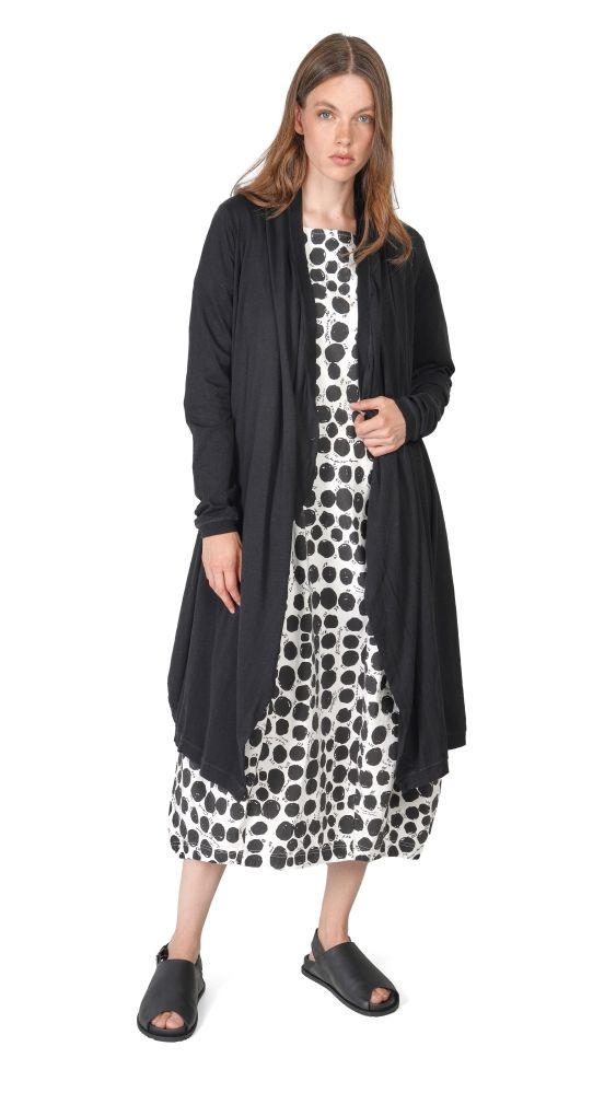 Frau trägt langes schwarzes Cape über polka-dot Kleid, schwarze Sandalen.
