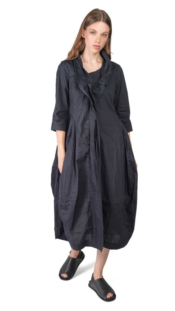 Langer, dunkler oversized-Mantel mit Schlitzpassen und dreiviertel Ärmeln, kombiniert mit schwarzen Sandalen.