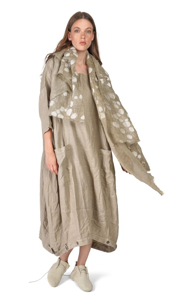Frau trägt langes, beige Kleid mit Blumenmuster auf den Ärmeln, kombiniert mit flachen Schuhen.