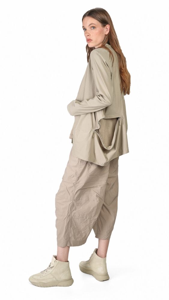 Frau trägt bequeme beige oversized Bluse mit weiten Hosen und Sneakern, lässiger Look.