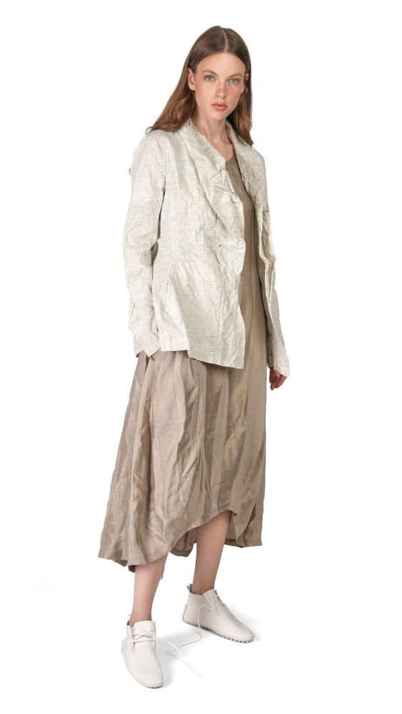 Frau trägt beiges, langes, weites Kleid mit oversized Bluse und weißen Sneakern.
