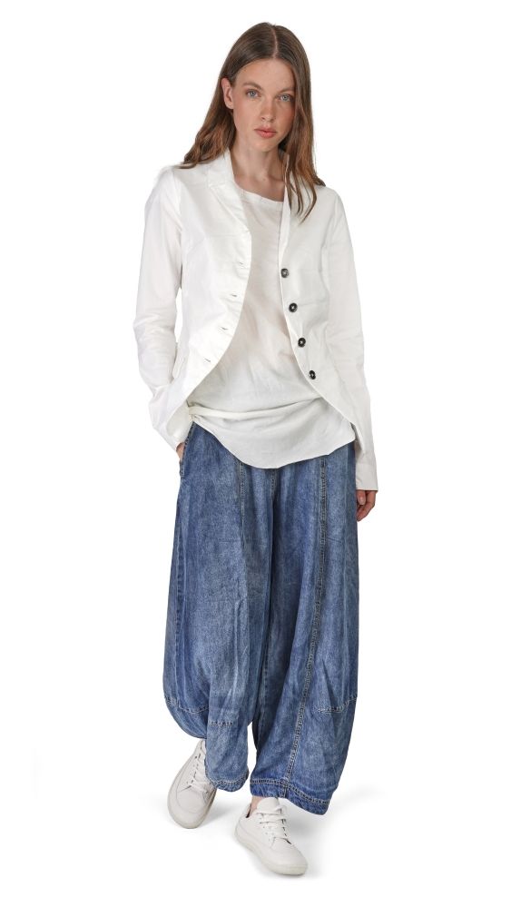 Frau trägt weiße Bluse mit Jacke, weite Jeanshose und weiße Sneaker, lässiger Stil.