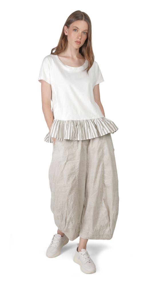 Frau trägt weißes T-Shirt mit gestreifter Puffhose und weißen Sneakern.