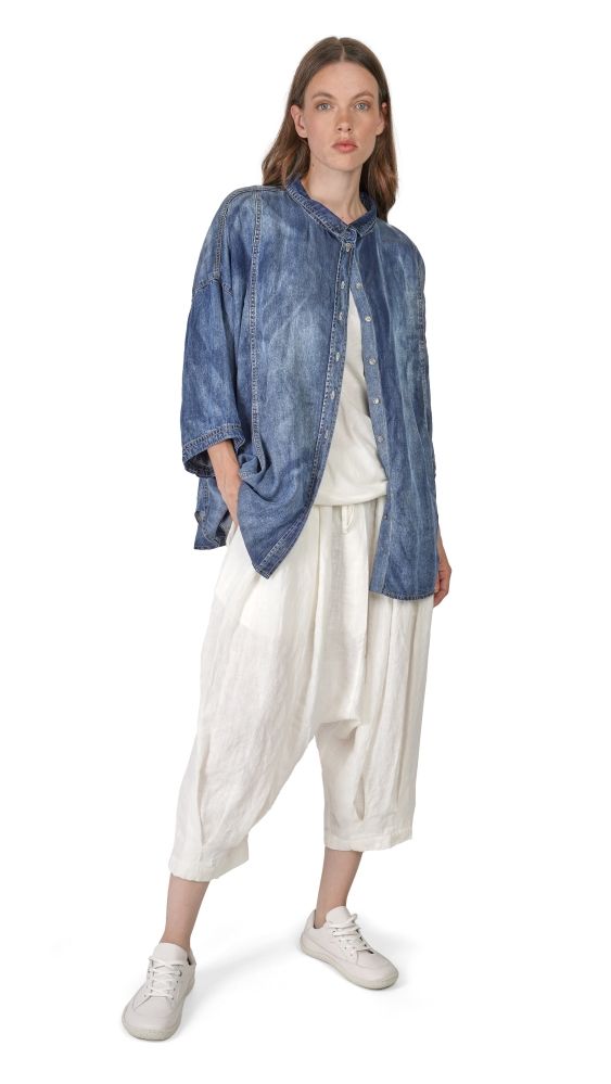 Frau trägt oversized blaue Denim-Jacke mit weißem Top und weiten Hosen, weiße Sneakers.