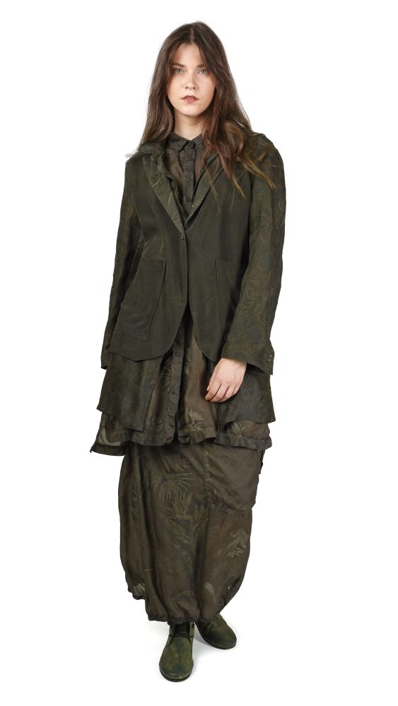 Frau trägt oversized grün-schwarzes Patchwork-Jacket mit weitem Rock und grünen Stiefeln.