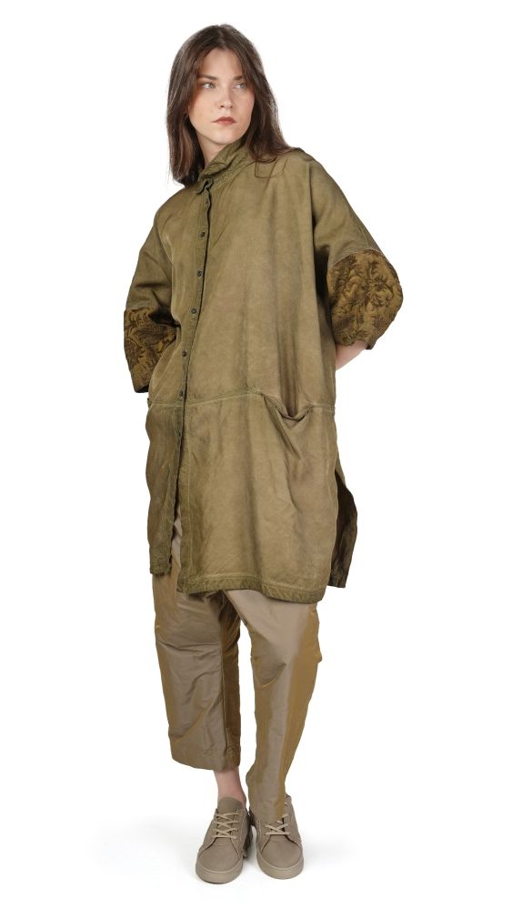Person trägt olivgrünen oversized Mantel mit weiten Hosen und flachen Schuhen.