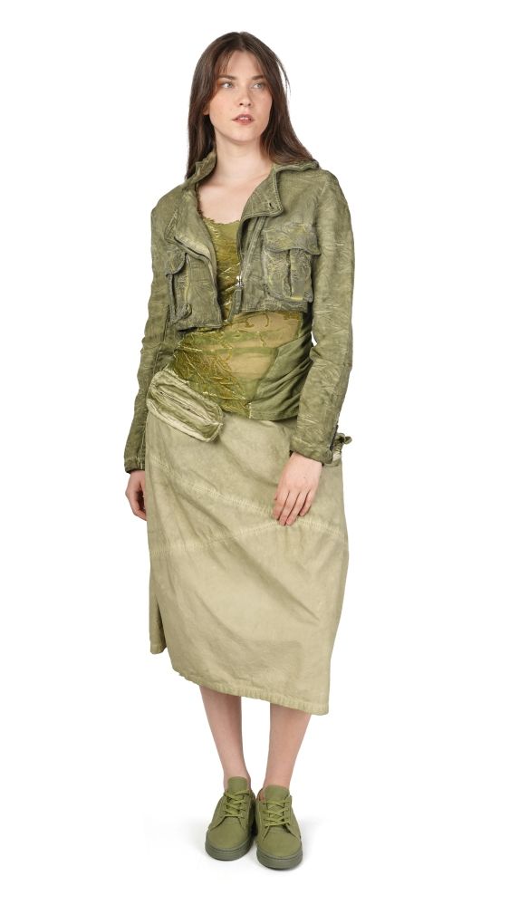 Frau trägt olivgrünes Crop-Jacke mit Westentaschen, langer Wickelrock und grüne Sneakers, elegant-lässig.