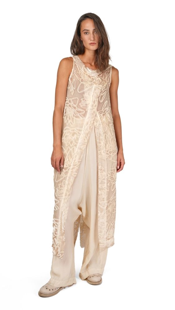 Frau trägt luftiges, beige-weißes Kleid mit floralem Muster und Sandalen.