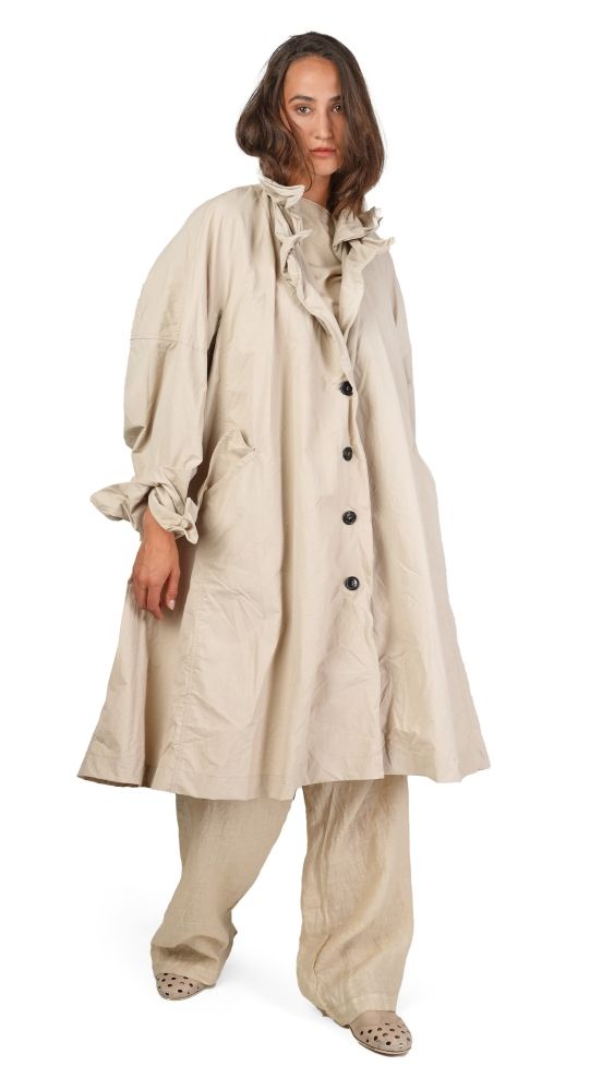 Vintage-Look: Frau in beige Überkleid mit Rüschen, weiten Hosen und flachen Schuhen.