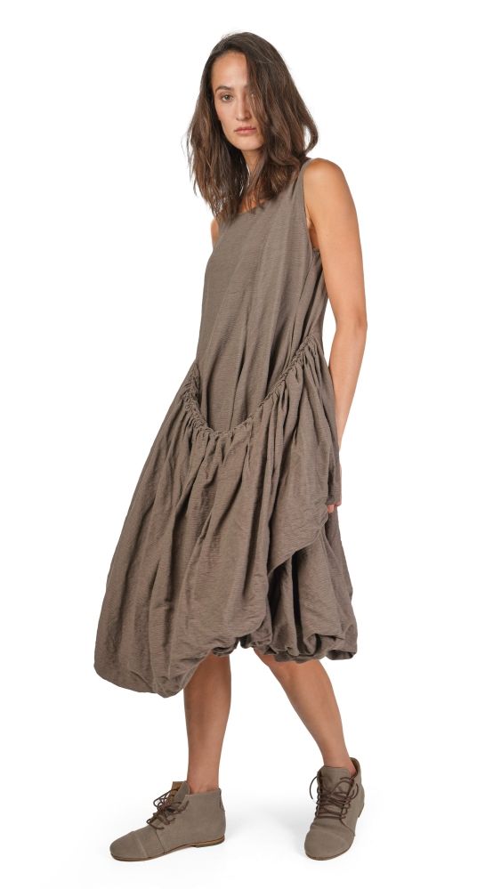 Frau trägt beiges, weites Schlabberkleid mit Schlitz und bequemen Schuhen.