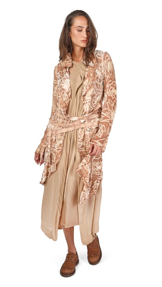 Frau trägt langes, gemustertes Cape über durchsichtigem Kleid, beige, mit braunen Stiefeln.