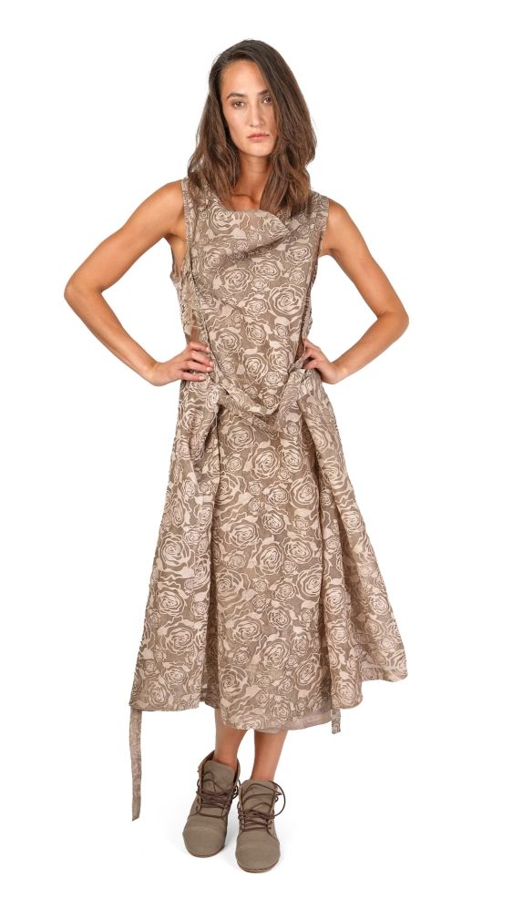 Frau trägt langes, gemustertes Kleid mit Schlitz und bequemen Schuhen, hands on hips.