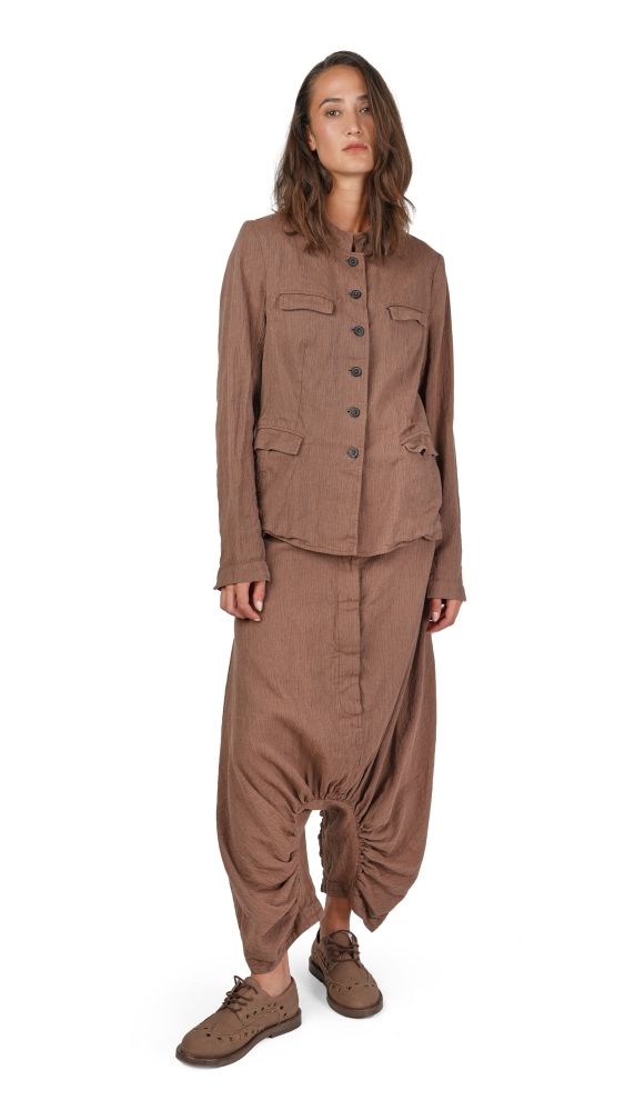 Frau trägt braunes oversized Jumpsuit-Kleid mit weiten Hosenbeinen und flache Schuhe.