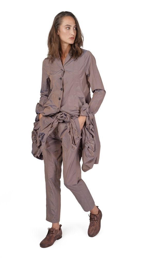 Frau trägt oversized beige Kleidung mit weitem Hemd und weiten Hosen, kombiniert mit braunen Stiefeln.