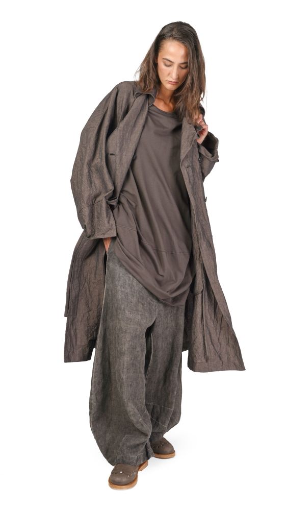 Frau trägt oversized graues Ensemble mit weitem Mantel und weiten Hosen, nachdenklich.
