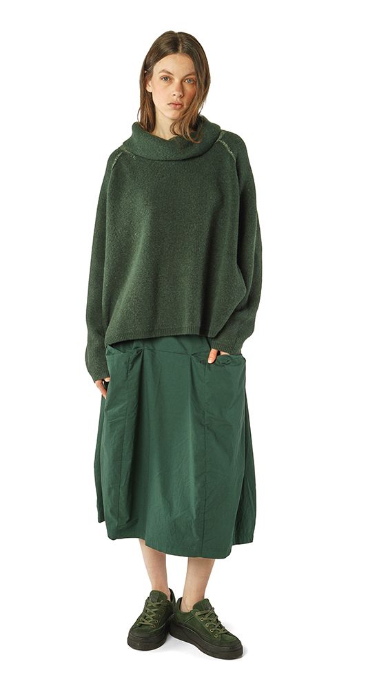 Frau trägt oversized grünen Pullover mit hochgeschlagenem Kragen und langem grünem Wickelrock, grüne Sneakers.