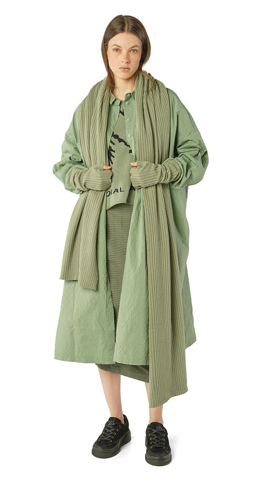 Person trägt oversized mintgrünen Strickmantel mit weitem Schnitt und schwarze Sneakers.