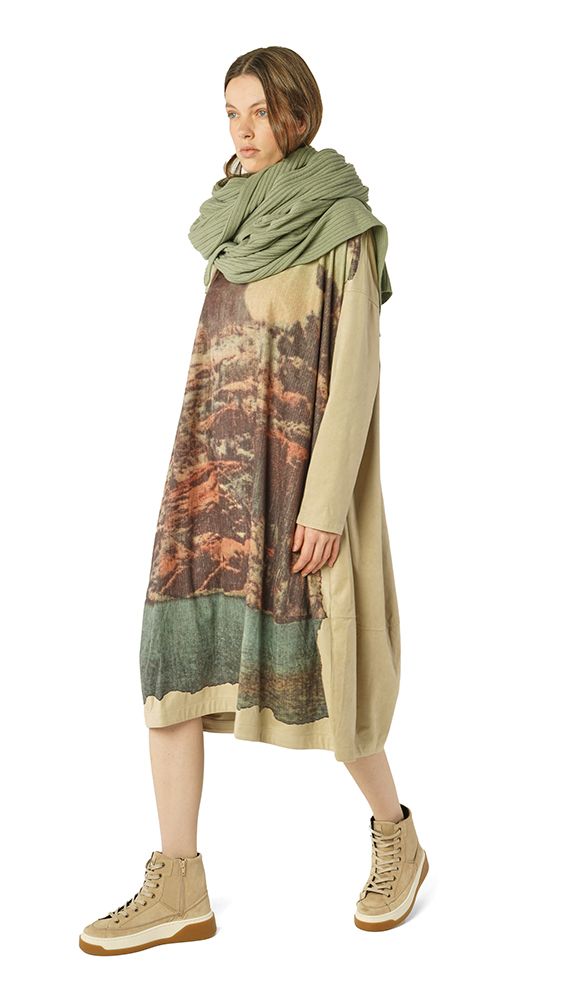 Frau trägt oversized Kleid mit Tierprint und grünem Schal, beige Sneakers.