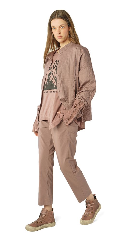 Frau trägt oversized beige Shirt mit Aufdruck, weite beige Jogginghose und braune Sneakers.