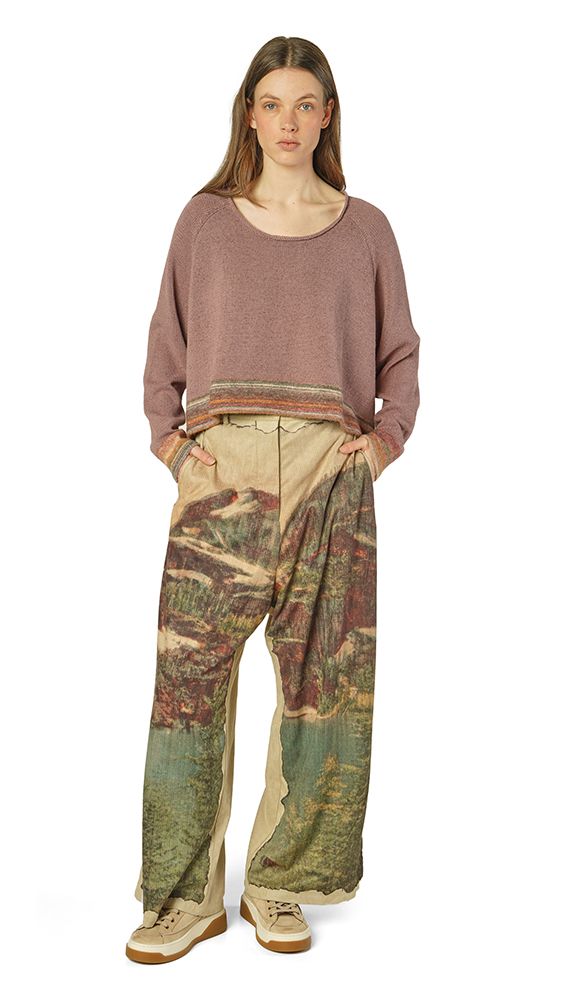 Person trägt oversized Pullover mit weiten, gemusterten Hosen und Sneakern.