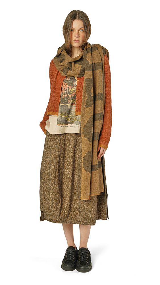 Frau trägt langes, gemustertes Kleid mit Schal und schwarzen Stiefeln, bohemian-inspiriert.