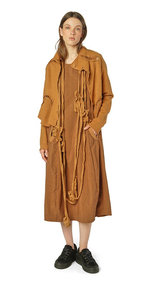 Lange, beige Strickjacke mit Fransen und Kordel-Akzenten, kombiniert mit schwarzen Sneakern.
