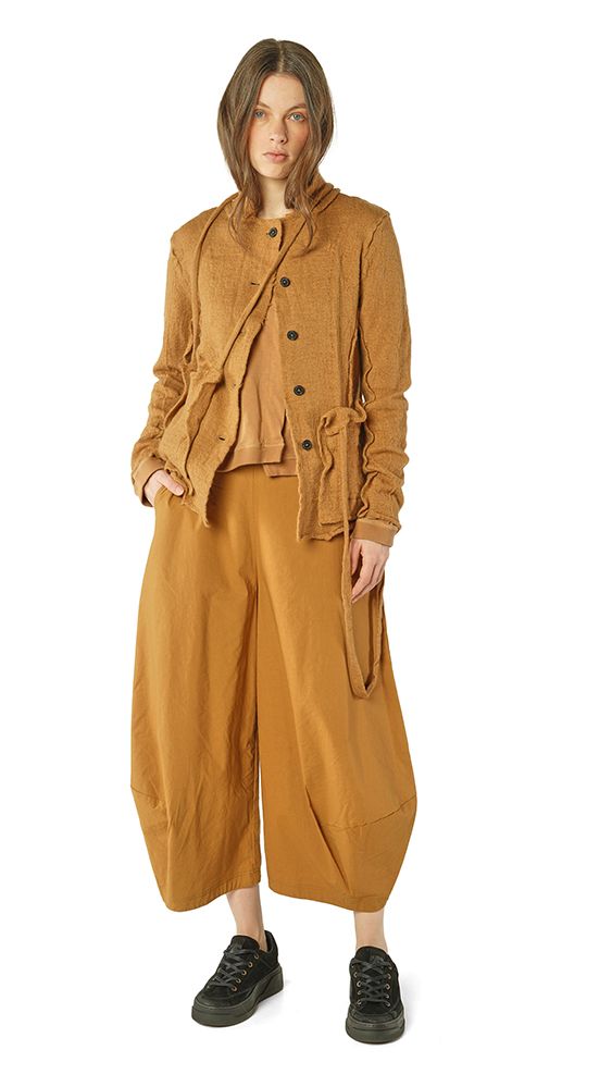 Frau trägt oversized beige Jacke mit Weste, weite Hosen und schwarze Sneaker.