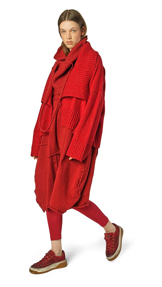 Frau trägt oversized roten Wollmantel mit langen Ärmeln und roten Stiefeln, lässig posierend.