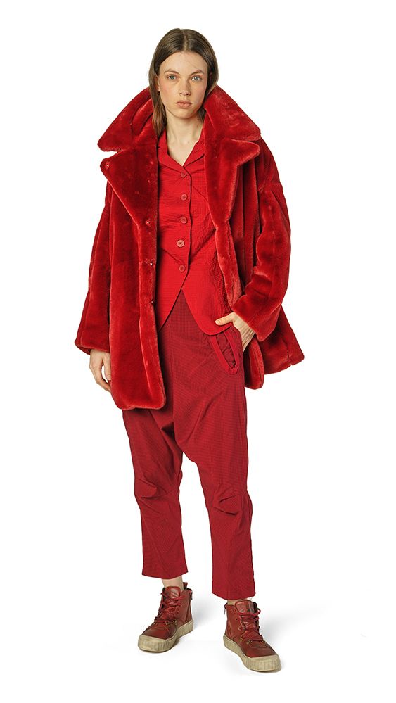 Frau trägt knielanges rot-samtiges Ensemble mit oversized Jacke und robusten Stiefeln.