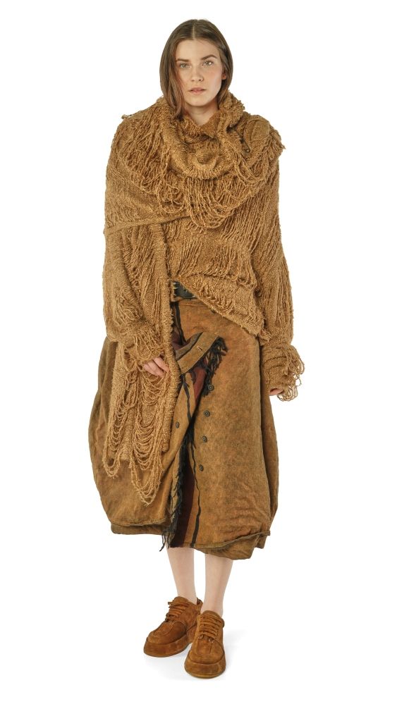 Frau trägt oversized braunes Wollkleid mit Fransen und Stiefeln, bohemian-inspiriert.