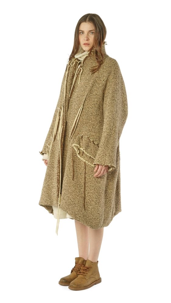 Frau trägt langen, beige-gestreiften Wollmantel mit Gürtel und braunen Stiefeln.