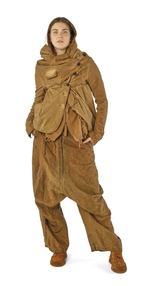 Person trägt altmodische, beige Overall-Kombination mit Kapuze und Accessoires.