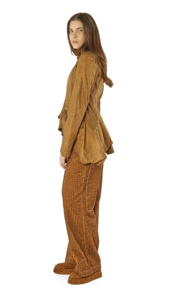 Person trägt beige Bluse mit weitem Schnitt und passende karierte Hosen, steht seitlich.