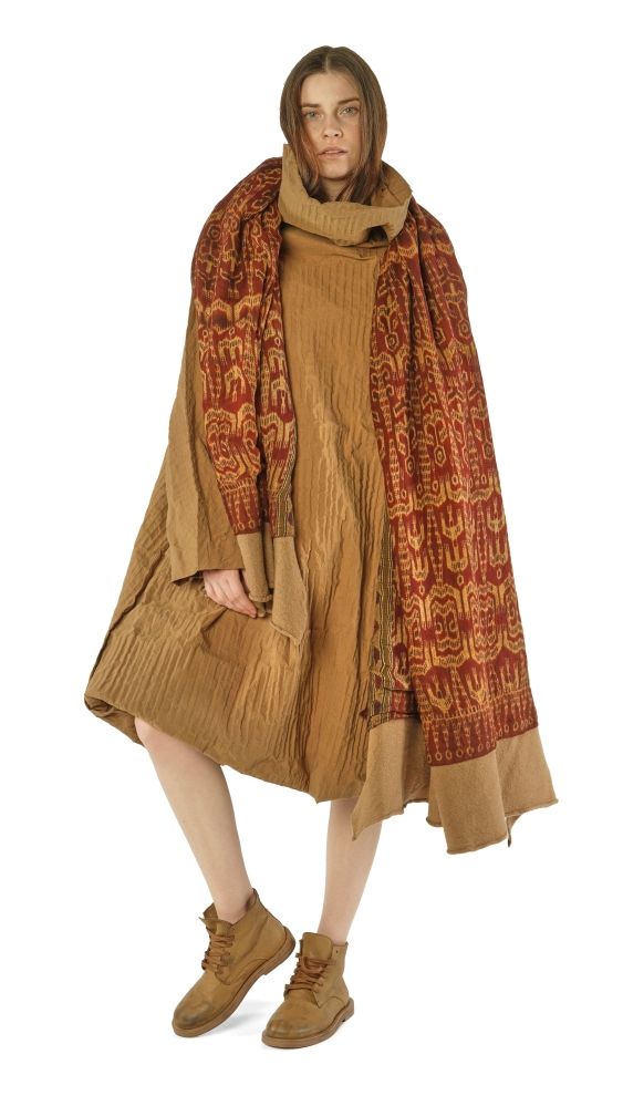 Person trägt langen, gemusterten Poncho mit Fransen und beigen Schuhen, elegant und lässig kombiniert.