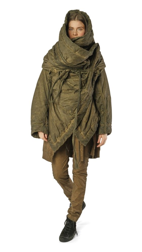 Frau trägt oversized olivgrünen Daunenmantel mit Kapuze und beigen Leggings, schwarze Stiefel.