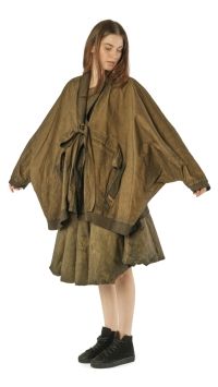 Frau trägt oversized olivgrünes Cape-Kleid mit Gürtel und schwarzen Stiefeln.