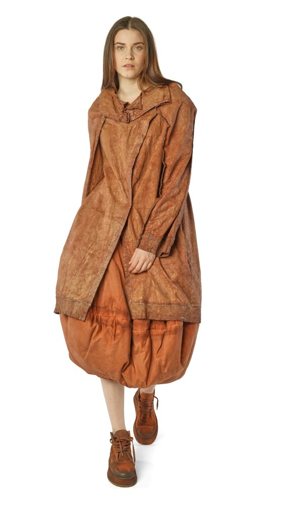Frau trägt oversized braunes Lederkleid mit weitem Schnitt und braunen Stiefeln.
