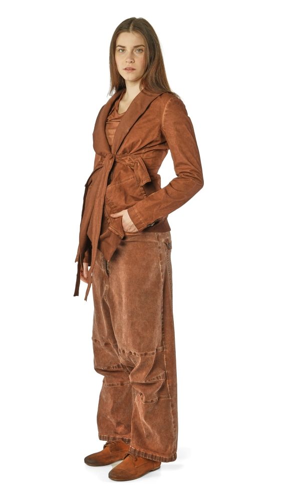 Person trägt braune, weite Lederhose mit langem Jackett und Stiefeln, stehend.