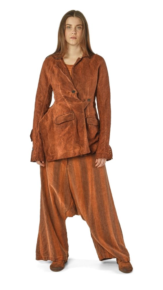 Frau trägt braunen oversize Veloursanzug mit weitem Hosenbein und flachen Schuhen.