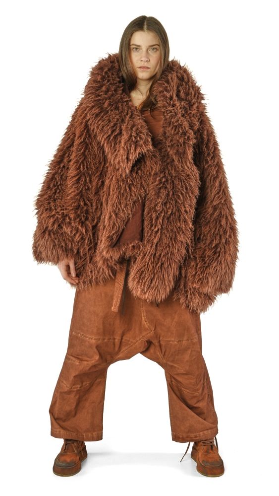 Person trägt oversized braunen Fake-Fell-Mantel mit weiten braunen Hosen und robusten Schuhen.